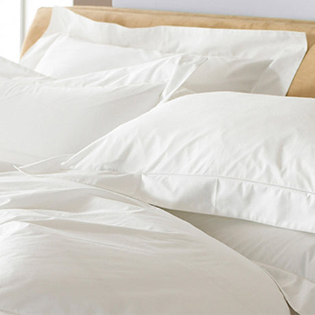 Oxford Plain Cotton Pillowcase Pair in white on a bed, showing the flat Oxford border edging and soft cotton sateen finish against white bedding.