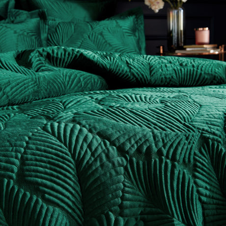 Palmeria Velvet Jungle Duvet Cover Set in emerald green, quilted palm-leaf pattern raised on velvet fabric, styled on a bed with matching pillowcases in a dark bedroom setting.