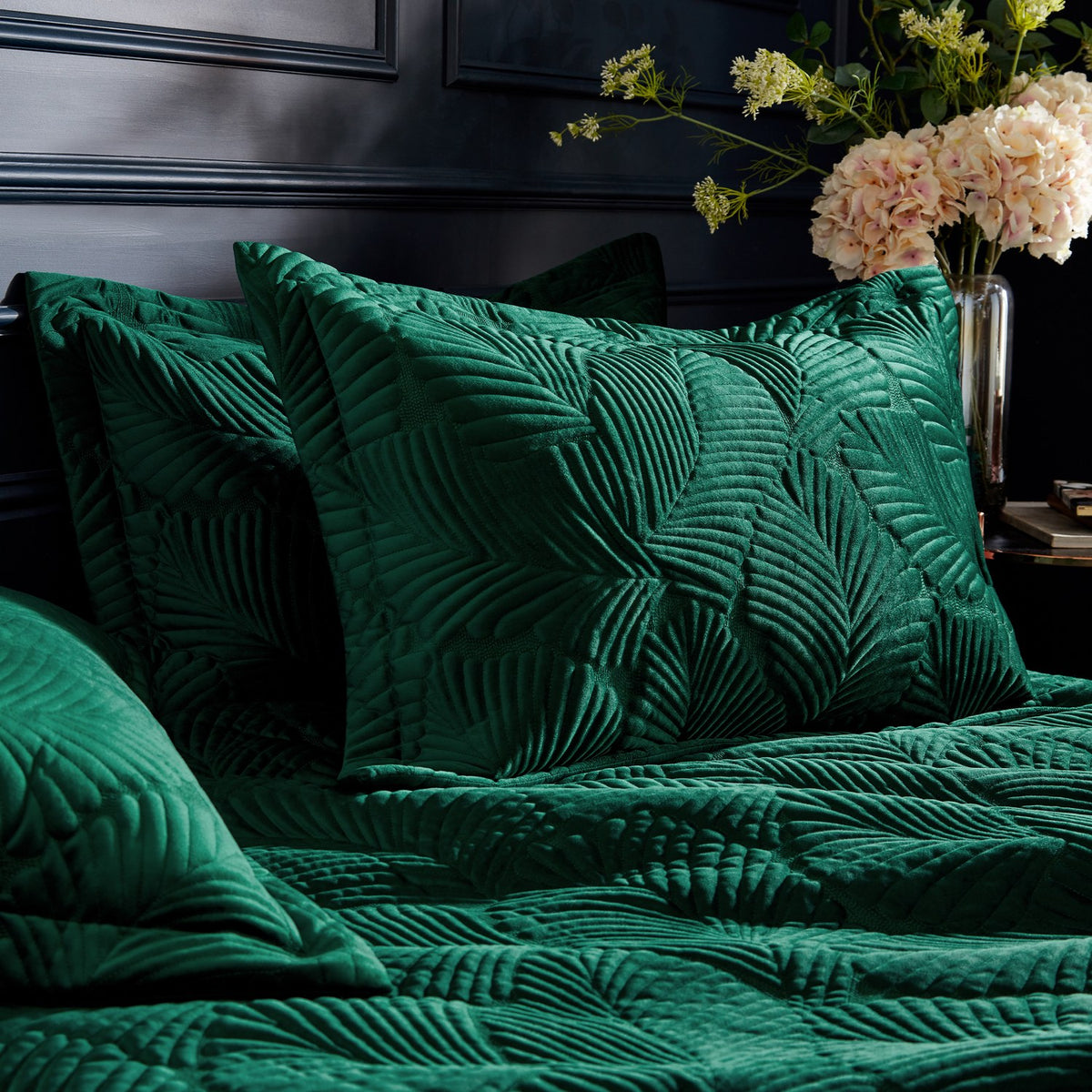 Palmeria Velvet Jungle Duvet Cover Set in emerald, showing quilted palm-leaf embroidered velvet pillowcases and duvet on a bed in a dark bedroom setting.