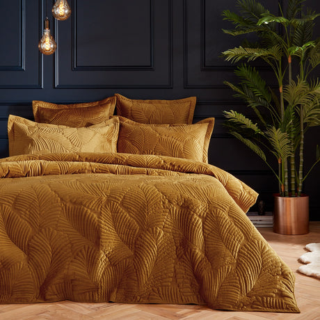 Palmeria Velvet Jungle Duvet Cover Set in gold, quilted palm-leaf pattern on velvet, styled with matching pillowcases on a bed in a dark-panelled bedroom.
