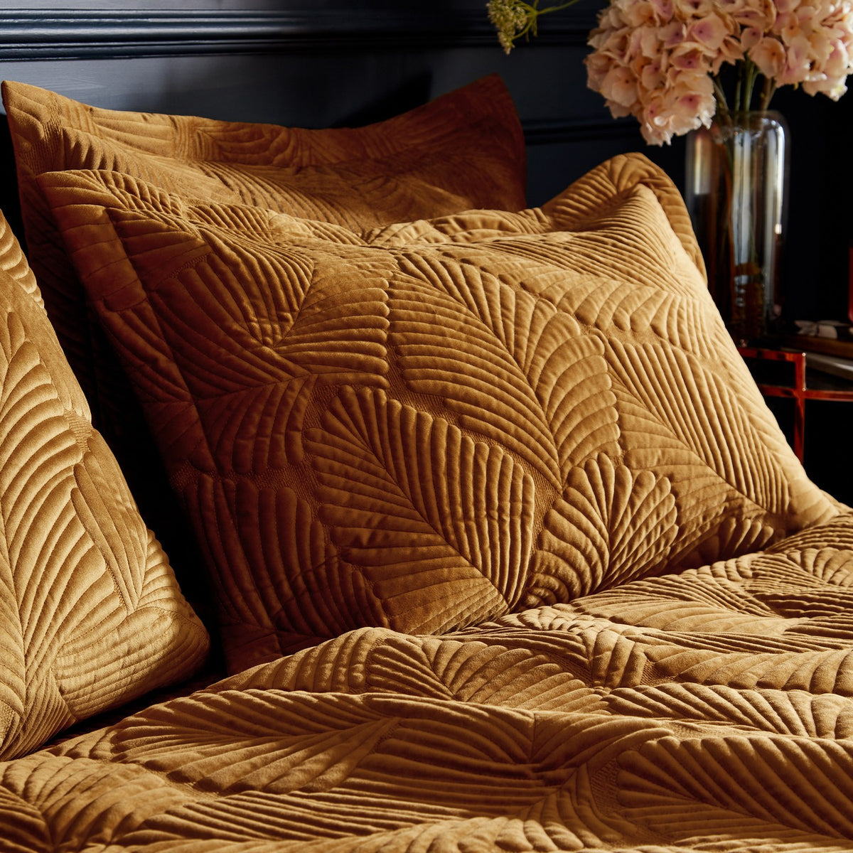 Palmeria Velvet Jungle Duvet Cover Set in gold, shown on a bed with matching pillowcases featuring a quilted palm-leaf pattern in a dark-toned bedroom setting.