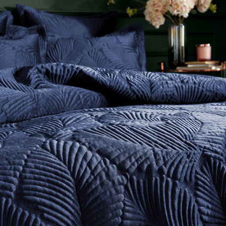 Palmeria Velvet Jungle Duvet Cover Set in navy, showing quilted velvet fronds on pillowshams and duvet, styled on a bed with flowers in the background.