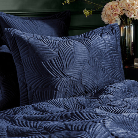 Palmeria Velvet Cotton Pillowcase Pair in navy, shown on bedroom pillows with a quilted, embroidered palm-leaf texture on the velvet front.