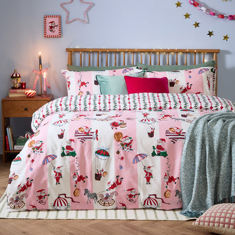 Passport To The North Pole Striped Duvet Cover Set in Candy Floss/Linen, shown on a bed with Santa scenes on pink and cream stripes, styled with green and pink cushions in a festive bedroom.