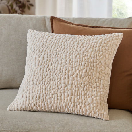 Pebble Linen Chenille Cushion in natural cream with raised pebble-textured chenille face, shown 45 x 45cm on a sofa beside a brown cushion.