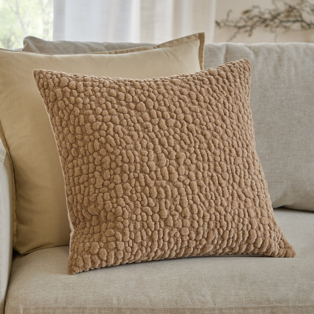 Pebble Linen Chenille Cushion in stone, 45 x 45cm with textured, pebble-like chenille surface, shown on a beige sofa alongside a plain cream cushion.