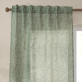 Perrie Leaf Floral Polyester Curtain Panel in forest green with a sheer, open-weave texture and back tab heading, hung from a wooden rod near a window.