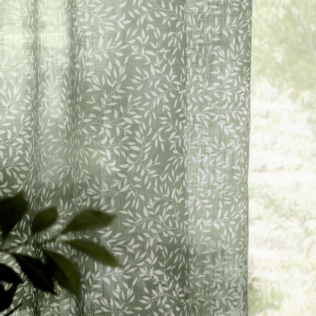 Perrie Leaf Floral Polyester Curtain Panel in forest green, sheer lightweight fabric with white trailing leaf print, shown draped near a window with soft natural light.