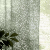 Perrie Leaf Floral Polyester Curtain Panel in forest green, sheer lightweight fabric with white trailing leaf print, shown draped near a window with soft natural light.
