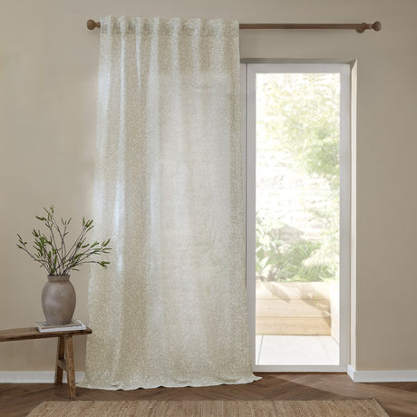 Perrie Leaf Floral Polyester Curtain Panel in natural, semi-sheer with small trailing leaf print, hung beside a glazed door in a living room setting.