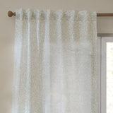 Perrie Leaf Floral Polyester Curtain Panel in natural hangs from a wooden pole with tab-top heading, showing a small trailing leaf print on a pale sheer fabric beside a window.