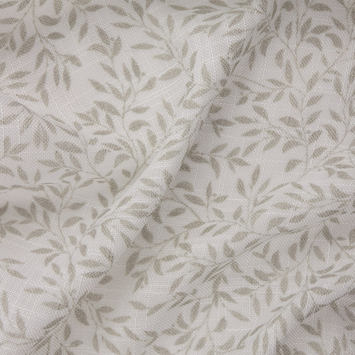 Perrie Leaf curtain panel in natural, close-up of woven polyester fabric with a small trailing leaf print on a pale ground, gathered in soft folds.