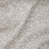 Perrie Leaf curtain panel in natural, close-up of woven polyester fabric with a small trailing leaf print on a pale ground, gathered in soft folds.