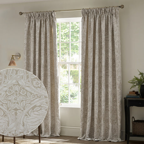 Pimpernel Jacquard Linen Pencil Pleat Curtains in beige, floral scrolling-stem pattern woven into the fabric, shown framing a window in a living room with a fabric swatch inset.
