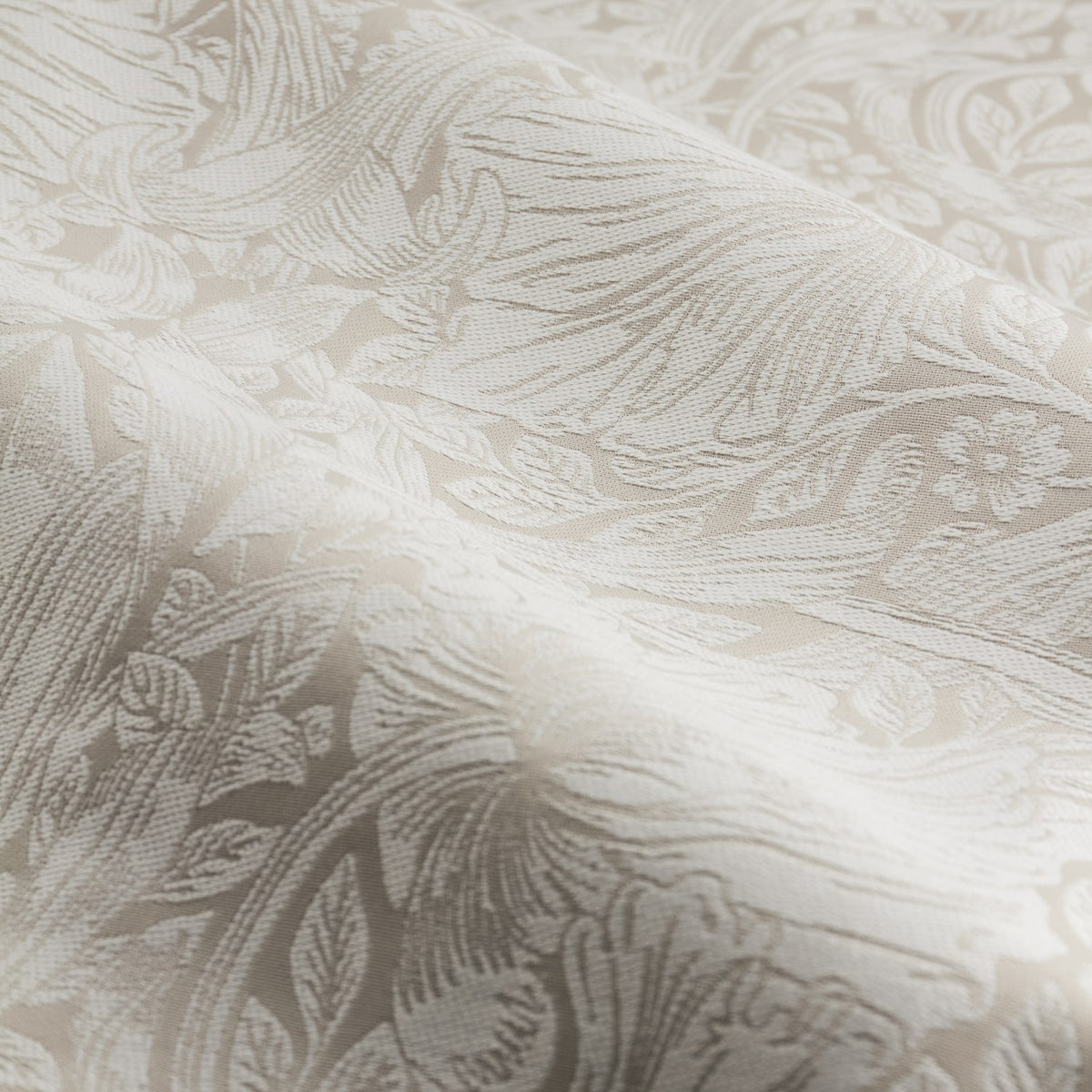 Close-up of Pimpernel Jacquard Linen Pencil Pleat Curtains in beige, showing the woven scrolling floral pattern with folds catching the light.