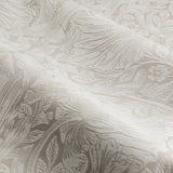 Close-up of Pimpernel Jacquard Linen Pencil Pleat Curtains in beige, showing the woven scrolling floral pattern with folds catching the light.