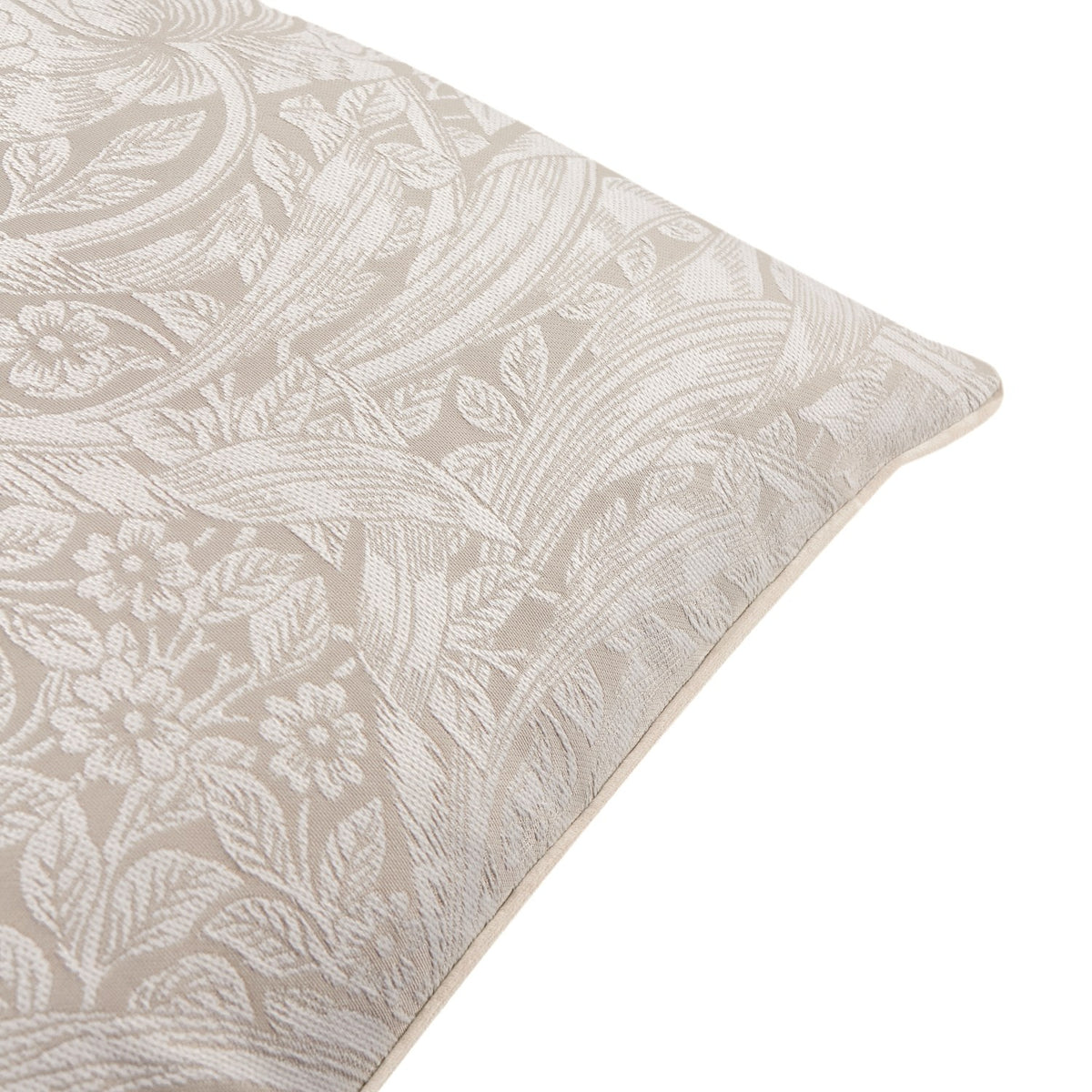 Pimpernel Jacquard Linen cushion corner detail, showing woven floral and foliage pattern in cream on a natural stone ground with piped edge finish.