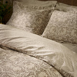 Pimpernel Cotton Floral Duvet Cover Set in natural and chocolate, shown on a bed with matching pillowcases featuring a Morris floral pattern in a bedroom setting.