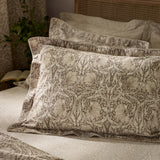 Pimpernel Cotton Floral Duvet Cover Set in natural and chocolate, styled on a bed with layered pillowcases showing the botanical print in a bedroom setting.
