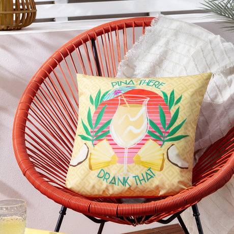 Pina There Abstract Polyester Cushion in yellow on an orange rattan chair, featuring a pina colada design with tropical leaves, pineapples and "Pina There Drank That" slogan.
