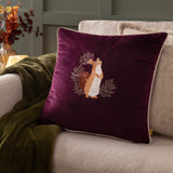 Pineberry Forest Animal Velvet Cushion in plum with embroidered red squirrel among foliage, cream piped edge, styled on a sofa with a green throw.