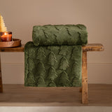 Pines Velvet Faux Fur Throw in forest green, folded and draped over a wooden bench, showing a raised tree pattern textured into the pile.