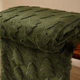 Pines Velvet Faux Fur Throw in forest green, folded over a wooden surface showing a raised tufted tree pattern on faux fur with a smooth velvet reverse.