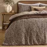 Perrie Leaf Cotton Ditsy Duvet Cover Set in chocolate brown with cream leaf print, shown on a bed with matching pillowcases in a bedroom setting.