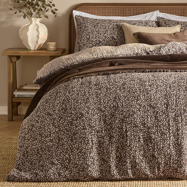 Perrie Leaf Cotton Ditsy Duvet Cover Set in chocolate brown with cream leaf print, shown on a bed with matching pillowcases in a bedroom setting.