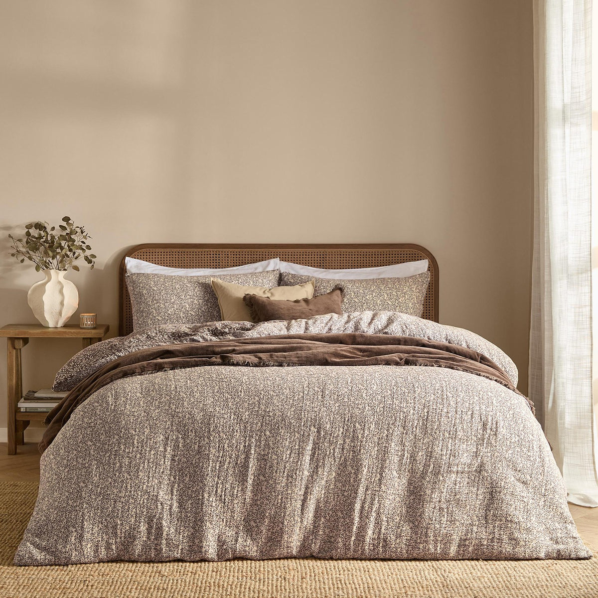 Perrie Leaf Cotton Ditsy Duvet Cover Set in chocolate brown with cream leaf print, styled on a bed with matching pillowcases and a brown throw in a bedroom setting.