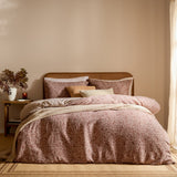 Perrie Leaf Cotton Ditsy Duvet Cover Set in cinnamon on a bed with matching pillowcases and cream cushions, styled in a bedroom with a cane headboard.