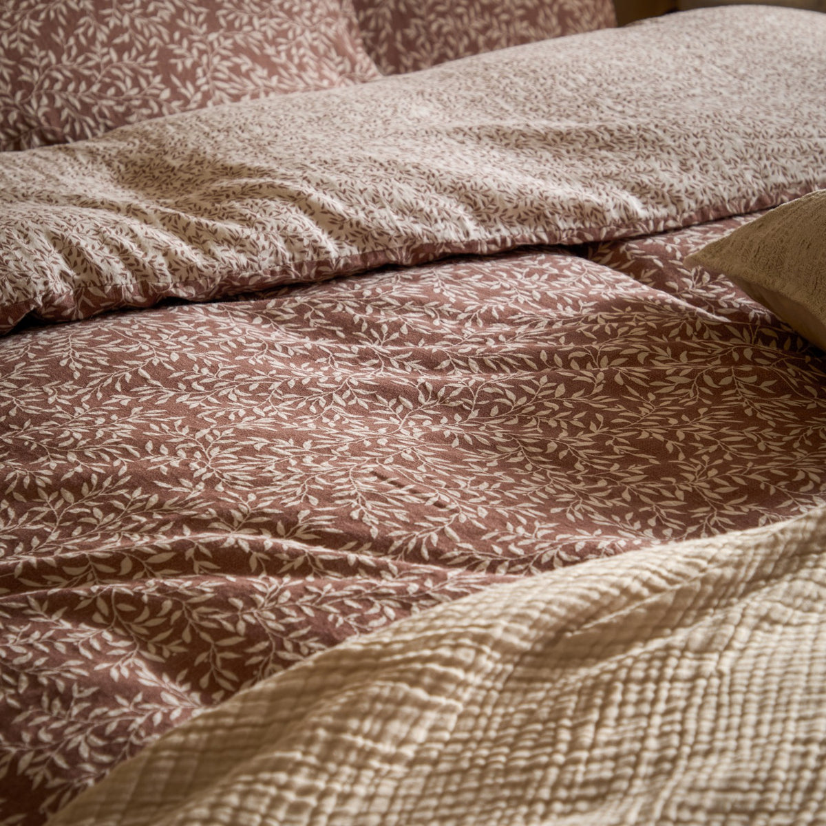 Perrie Leaf Cotton Ditsy Duvet Cover Set in cinnamon, rumpled cotton bedding with cream leaf sprig print, paired with a textured cream quilted throw on the bed.