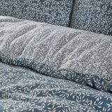 Perrie Leaf Cotton Ditsy Duvet Cover Set in Denim, close-up of crinkled cotton bedding with a small-scale cream leaf print on a blue ground, reverse side shown in plain denim blue.