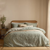 Perrie Leaf Cotton Ditsy Duvet Cover Set in Forest green, styled on a bed with matching pillowcases and cream cushions against a rattan headboard.