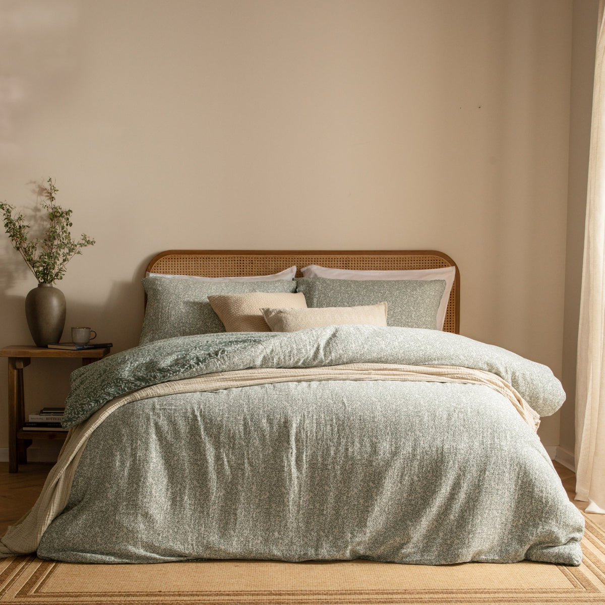 Perrie Leaf Cotton Ditsy Duvet Cover Set in Forest, styled on a bed with matching pillowcases and cushions in a rattan-headboard bedroom.