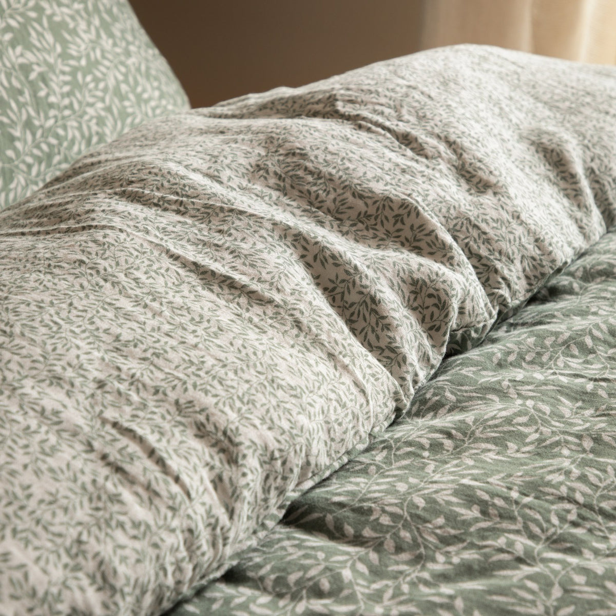 Perrie Leaf Cotton Ditsy Duvet Cover Set in Forest, close-up of crinkled cotton with a green leaf print on white and matching solid green reverse.