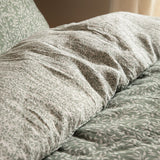 Perrie Leaf Cotton Ditsy Duvet Cover Set in Forest, close-up of crinkled cotton with a green leaf print on white and matching solid green reverse.