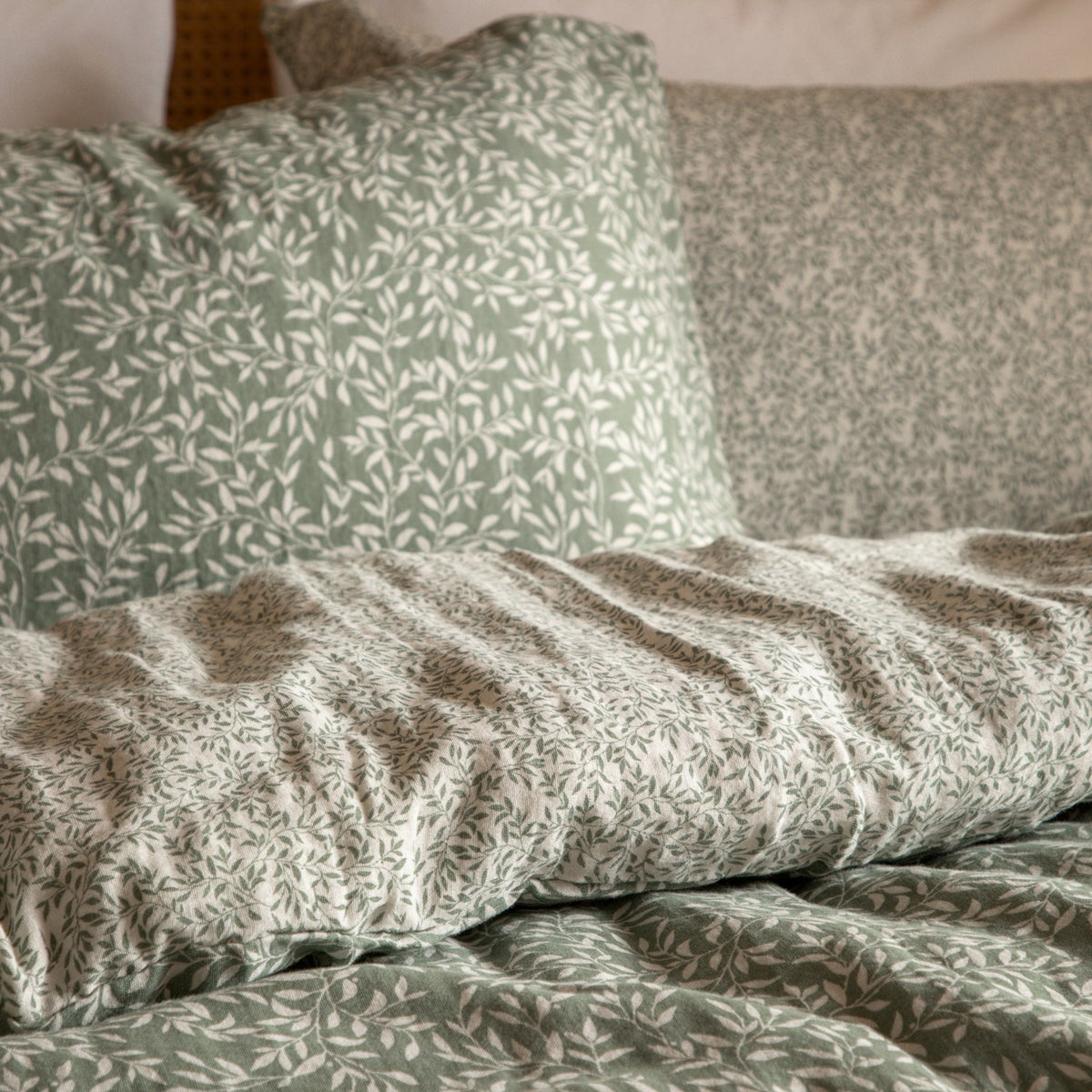 Perrie Leaf Cotton Ditsy Duvet Cover Set in Forest, showing green ditsy leaf print cotton pillowcases and duvet with a smaller-scale reverse pattern, styled on a bed.