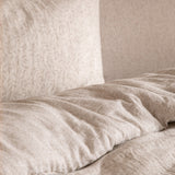Perrie Leaf Cotton Ditsy Duvet Cover Set in natural, close-up of crinkled muslin cotton bedding with a small leaf print on a pale neutral ground.