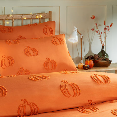 Pumpkin Fields tufted duvet cover set in orange, showing raised pumpkin motifs on the duvet and matching pillowcases, styled on a bed in a warmly lit bedroom setting.