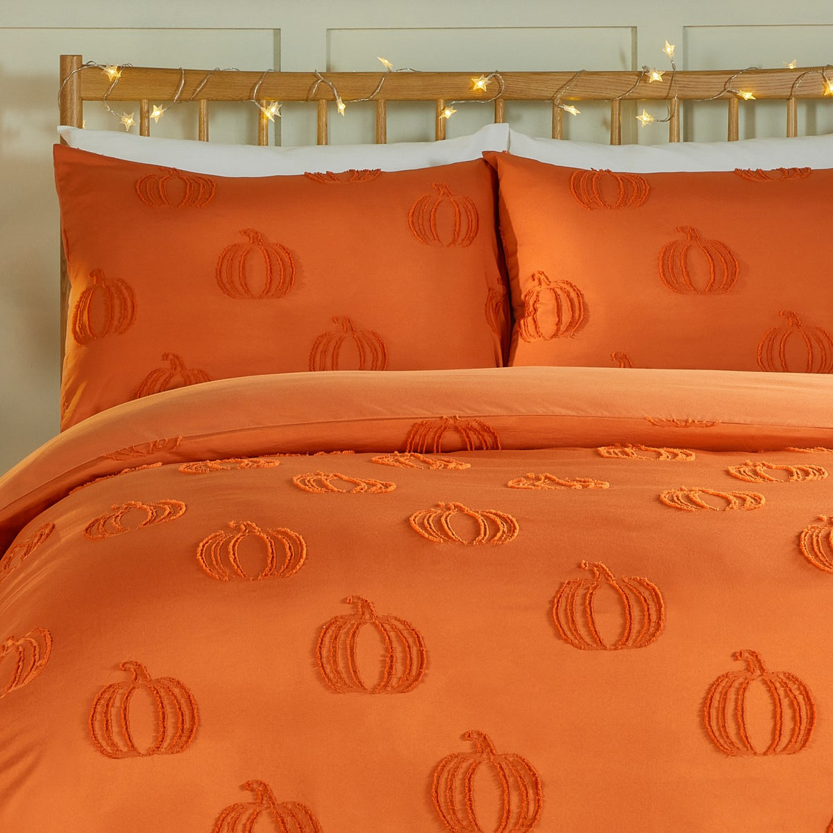 Pumpkin Fields tufted duvet cover set in orange on a bed with matching pillowcases, showing a raised pumpkin motif on plain polyester fabric.
