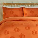 Pumpkin Fields tufted duvet cover set in orange on a bed with matching pillowcases, showing a raised pumpkin motif on plain polyester fabric.