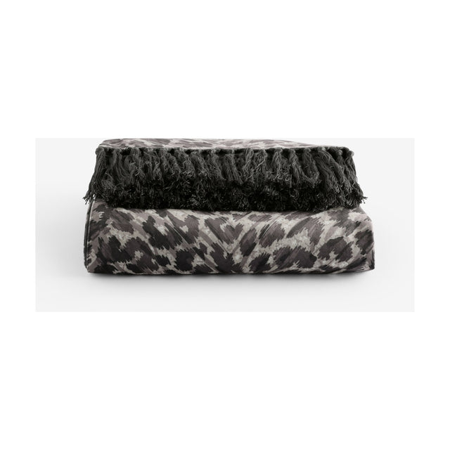 Pokot Animal Velvet Throw in monochrome, folded to show leopard-print grey and black velvet with knotted black fringe trim, on a plain white background.