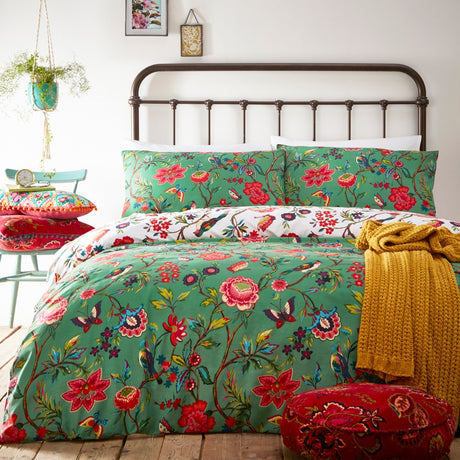 Pomelo Printed Floral Duvet Cover Set in Verdi green, styled on a bed with matching pillowcases, patterned cushions, a mustard throw and red footstool in a bedroom setting.