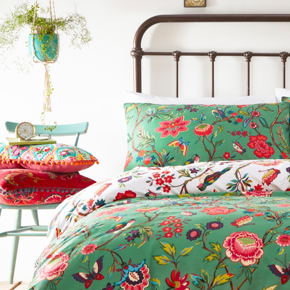 Pomelo Printed Floral Duvet Cover Set in Verdi, shown on a bedroom bed with green ground and red, pink and blue floral, bird and butterfly print, styled with matching pillowcase.