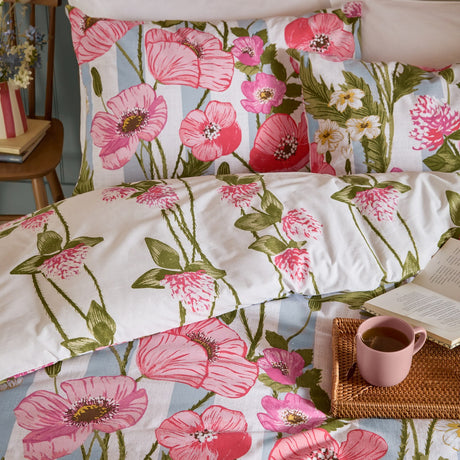 Poppy Trail reversible floral duvet cover set in pink, coral and green, shown styled on a bed with matching pillowcases in a bedroom setting.