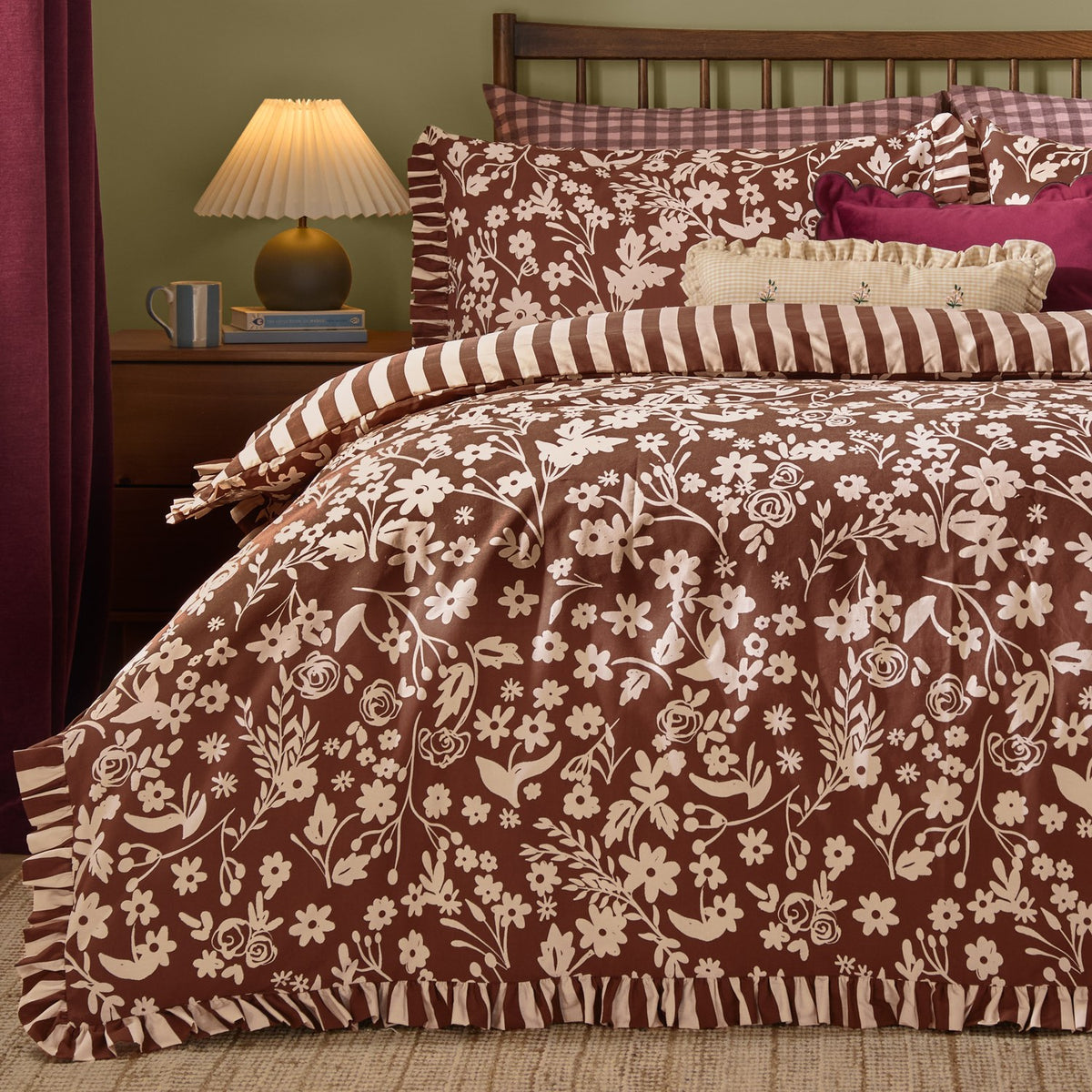Posie Reversible Floral Duvet Cover Set in chocolate brown with cream floral print, frilled edge trim and matching striped pillowcases on a bed in a bedroom setting.