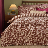 Posie Reversible Floral Duvet Cover Set in chocolate brown with cream floral print, frilled edge trim and matching striped pillowcases on a bed in a bedroom setting.