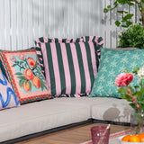 Palm Royale Stripe polyester cushion in forest green and pink with ruffle trim, styled on an outdoor sofa alongside patterned scatter cushions.