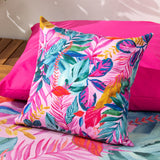 Psychedelic Jungle Reversible Polyester Cushion in Multi, a square outdoor cushion with a dense tropical leaf print in pink, teal, blue, green and gold, shown on a bright pink outdoor seat cushion.